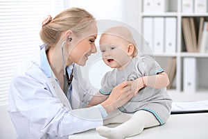 Pediatrician is taking care of baby in hospital. Little girl is being examine by doctor with stethoscope