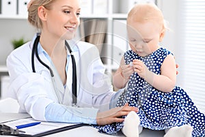 Pediatrician is taking care of baby in hospital. Little girl is being examine by doctor with stethoscope