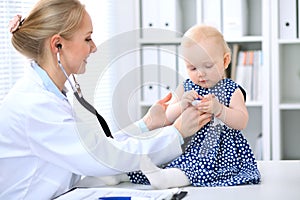 Pediatrician is taking care of baby in hospital. Little girl is being examine by doctor with stethoscope. Health care