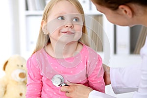 Pediatrician is taking care of baby in hospital. Little girl is being examine by doctor by stethoscope. Health care