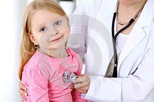 Pediatrician is taking care of baby in hospital. Little girl is being examine by doctor by stethoscope. Health care