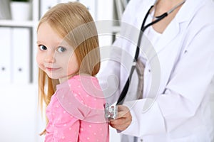 Pediatrician is taking care of baby in hospital. Little girl is being examine by doctor by stethoscope. Health care