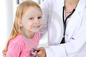 Pediatrician is taking care of baby in hospital. Little girl is being examine by doctor by stethoscope. Health care