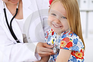 Pediatrician is taking care of baby in hospital. Little girl is being examine by doctor by stethoscope. Health care