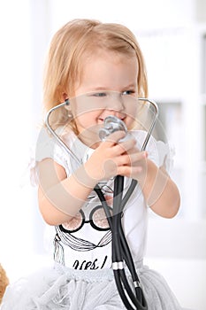 Pediatrician is taking care of baby in hospital. Little girl is being examine by doctor with stethoscope. Health care