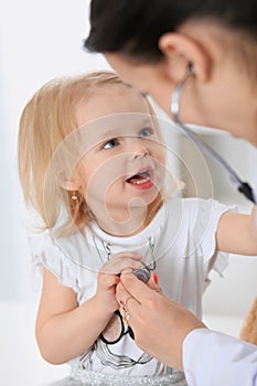 Pediatrician is taking care of baby in hospital. Little girl is being examine by doctor with stethoscope. Health care