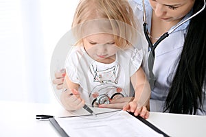 Pediatrician is taking care of baby in hospital. Little girl is being examine by doctor with stethoscope. Health care