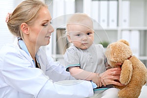 Pediatrician is taking care of baby in hospital. Little girl is being examine by doctor with stethoscope. Health care