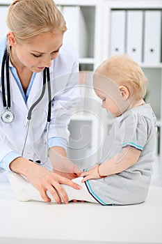 Pediatrician is taking care of baby in hospital. Little girl is being examine by doctor with stethoscope. Health care