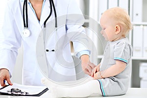 Pediatrician is taking care of baby in hospital. Little girl is being examine by doctor with stethoscope. Health care