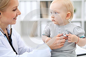 Pediatrician is taking care of baby in hospital. Little girl is being examine by doctor with stethoscope. Health care