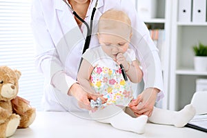 Pediatrician is taking care of baby in hospital. Little girl is being examine by doctor with stethoscope. Health care