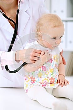 Pediatrician is taking care of baby in hospital. Little girl is being examine by doctor with stethoscope. Health care