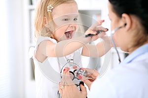 Pediatrician is taking care of baby in hospital. Little girl is being examine by doctor with stethoscope. Health care