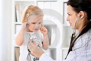 Pediatrician is taking care of baby in hospital. Little girl is being examine by doctor with stethoscope. Health care