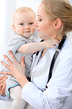 Pediatrician is taking care of baby in hospital. Little girl is being examine by doctor with stethoscope. Health care