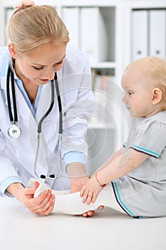 Pediatrician is taking care of baby in hospital. Little girl is being examine by doctor with stethoscope. Health care