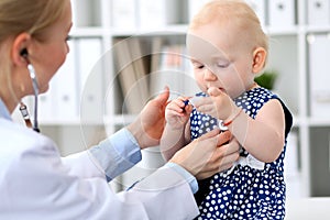 Pediatrician is taking care of baby in hospital. Little girl is being examine by doctor with stethoscope. Health care