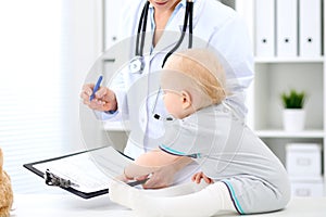 Pediatrician is taking care of baby in hospital. Little girl is being examine by doctor with stethoscope. Health care