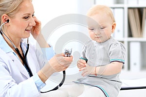 Pediatrician is taking care of baby in hospital. Little girl is being examine by doctor with stethoscope. Health care