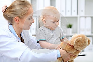 Pediatrician is taking care of baby in hospital. Little girl is being examine by doctor with stethoscope. Health care