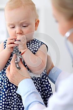 Pediatrician is taking care of baby in hospital. Little girl is being examine by doctor with stethoscope. Health care