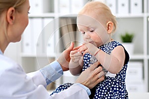 Pediatrician is taking care of baby in hospital. Little girl is being examine by doctor with stethoscope. Health care