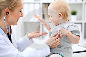 Pediatrician is taking care of baby in hospital. Little girl is being examine by doctor with stethoscope. Health care