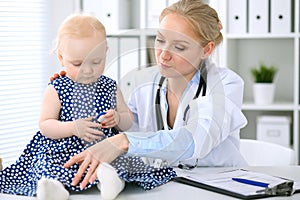 Pediatrician is taking care of baby in hospital. Little girl is being examine by doctor with stethoscope. Health care