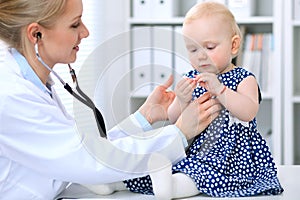 Pediatrician is taking care of baby in hospital. Little girl is being examine by doctor with stethoscope. Health care