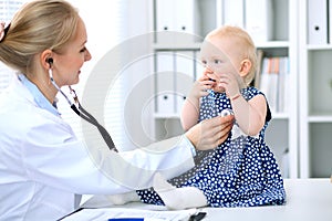 Pediatrician is taking care of baby in hospital. Little girl is being examine by doctor with stethoscope. Health care