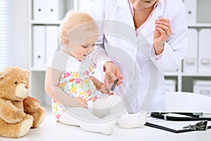 Pediatrician is taking care of baby in hospital. Little girl is being examine by doctor with stethoscope. Health care