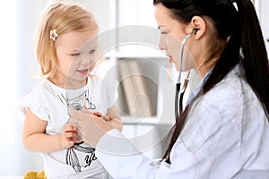 Pediatrician is taking care of baby in hospital. Little girl is being examine by doctor with stethoscope. Health care