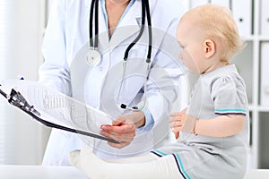 Pediatrician is taking care of baby in hospital. Little girl is being examine by doctor with stethoscope. Health care