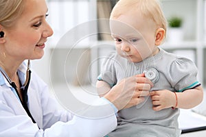 Pediatrician is taking care of baby in hospital. Little girl is being examine by doctor with stethoscope. Health care