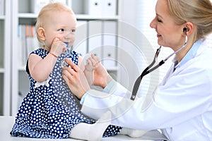 Pediatrician is taking care of baby in hospital. Little girl is being examine by doctor with stethoscope. Health care