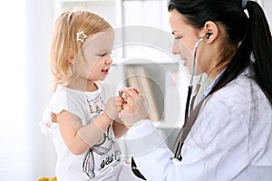 Pediatrician is taking care of baby in hospital. Little girl is being examine by doctor with stethoscope. Health care