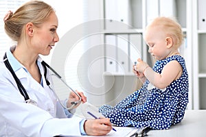 Pediatrician is taking care of baby in hospital. Little girl is being examine by doctor with stethoscope. Health care