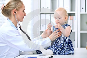 Pediatrician is taking care of baby in hospital. Little girl is being examine by doctor with stethoscope. Health care