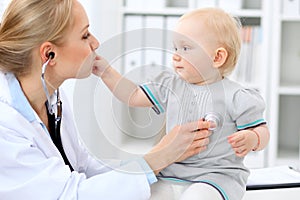 Pediatrician is taking care of baby in hospital. Little girl is being examine by doctor with stethoscope. Health care