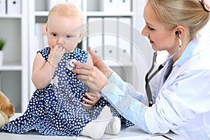 Pediatrician is taking care of baby in hospital. Little girl is being examine by doctor with stethoscope. Health care