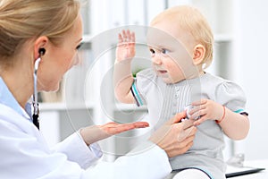 Pediatrician is taking care of baby in hospital. Little girl is being examine by doctor with stethoscope. Health care