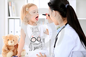 Pediatrician is taking care of baby in hospital. Little girl is being examine by doctor with stethoscope. Health care