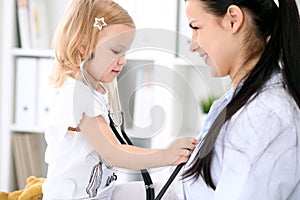 Pediatrician is taking care of baby in hospital. Little girl is being examine by doctor with stethoscope. Health care