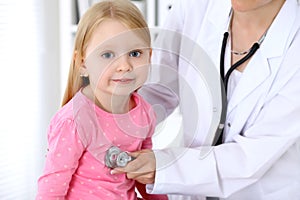 Pediatrician is taking care of baby in hospital. Little girl is being examine by doctor by stethoscope. Health care