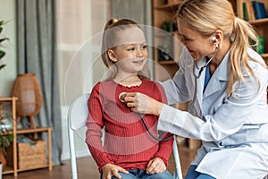 Pediatrician visiting her little patient at home, woman in uniform listening to child patient breath with stethoscope