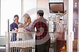 Pediatrician Visiting Parents And Child In Hospital Bed