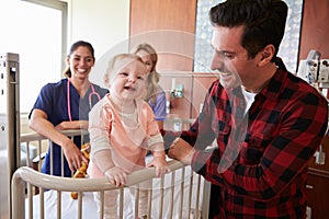 Pediatrician Visiting Parents And Child In Hospital Bed