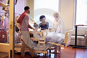 Pediatrician Visiting Parents And Child In Hospital Bed