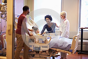 Pediatrician Visiting Parents And Child In Hospital Bed